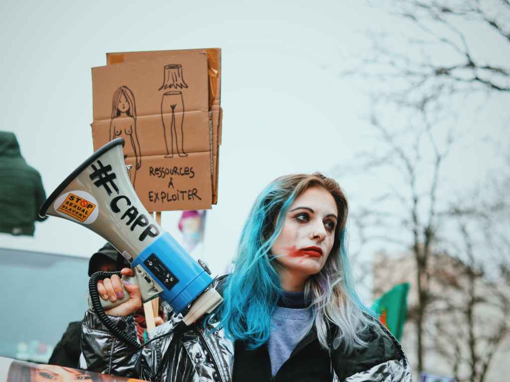 young woman with painted face and megaphone during sexual exploitation protest